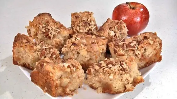 Apple butterscotch bars on a white plate with an apple in the background.