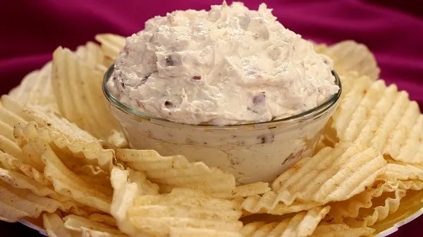 Clear bowl filled with bacon horseradish dip surrounded by potato chips.