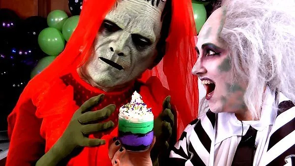 Amy and sidekick Frankie dressed as Beetlejuice characters holding a no bake Oreo cheesecake cup.