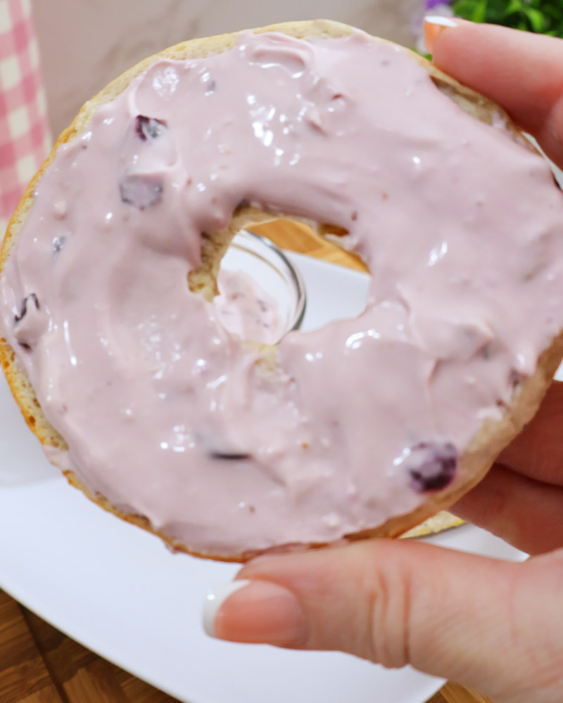 Half of a bagel slathered with homemade blueberry cream cheese spread