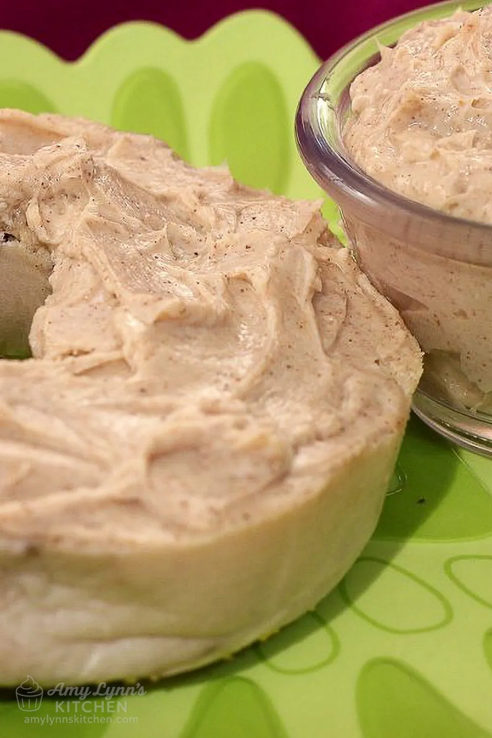 Close-up of a toasted bagel spread with homemade brown sugar cinnamon cream cheese, shown with extra spread in a small glass bowl.
