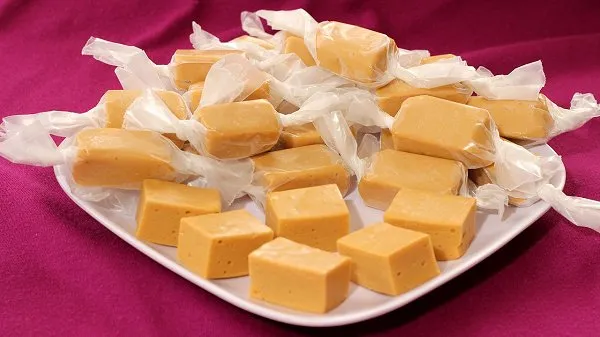 Butterscotch marshmallow chews piled on a white plate.