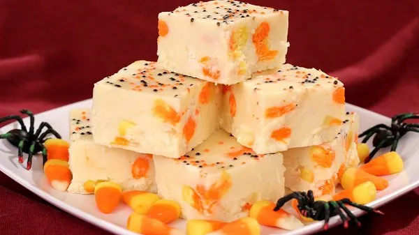 Delicious candy corn fudge with spooky Halloween sprinkles stacked on a white plate.