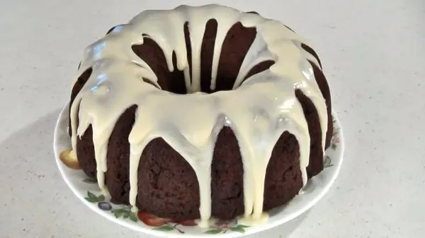 Chocolate chip bundt cake topped with a white chocolate glaze on a plate.