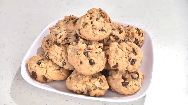 Homemade chocolate chip cookies piled high on a white plate.