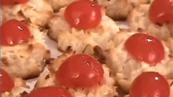 Closeup of rows of coconut macaroons topped with cherries.