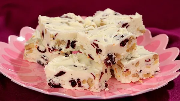 Cranberry walnut fudge stacked on a pink plate.