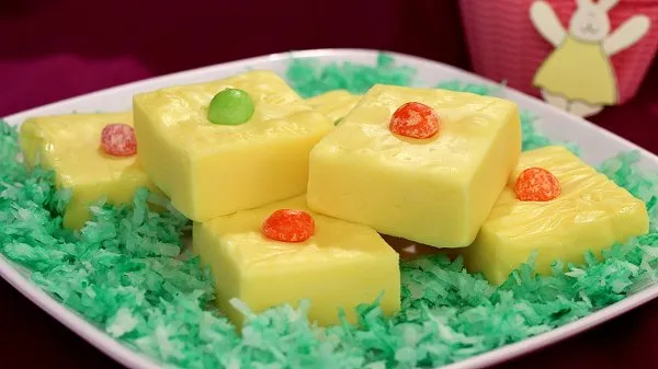 Plate of Easter lemon fudge topped with jelly beans on green tinted, flaked coconut.