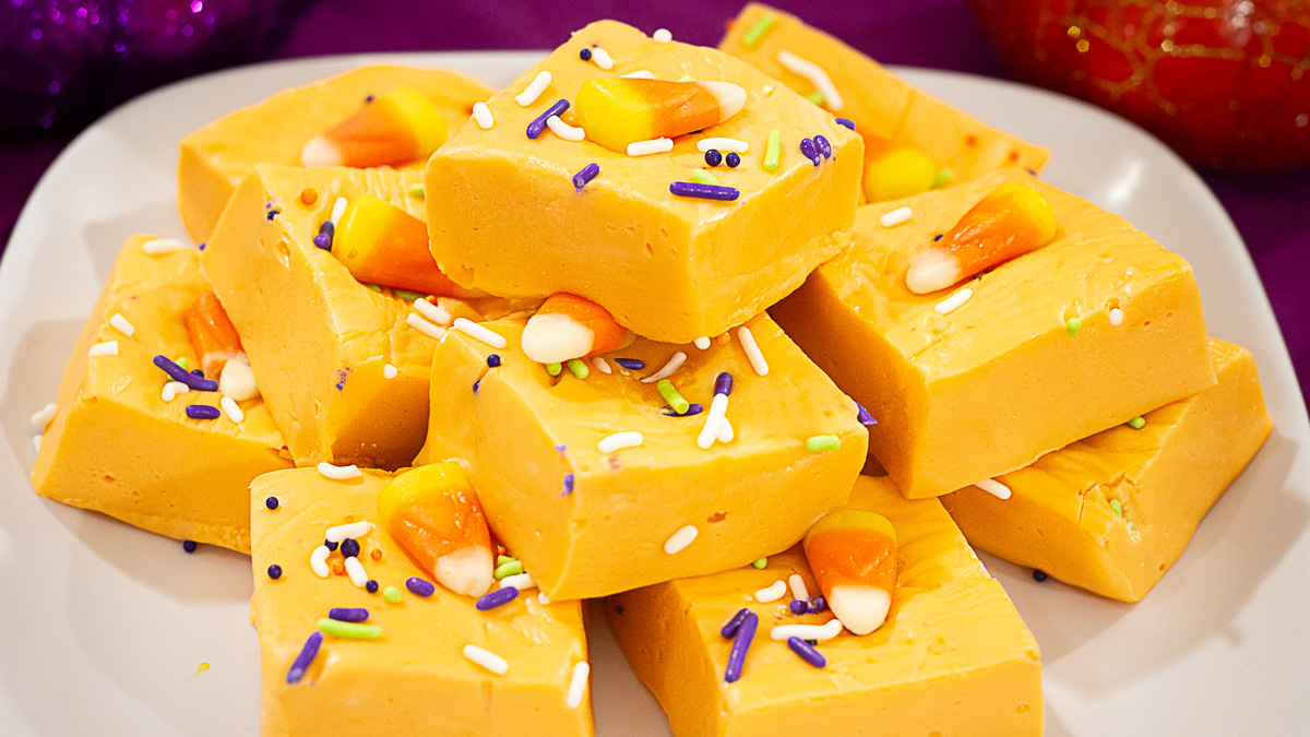 Delicious and fun Halloween Orange Fudge stacked on a white plate.