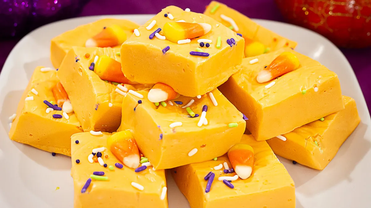 Delicious candy corn fudge with spooky Halloween sprinkles stacked on a white plate.