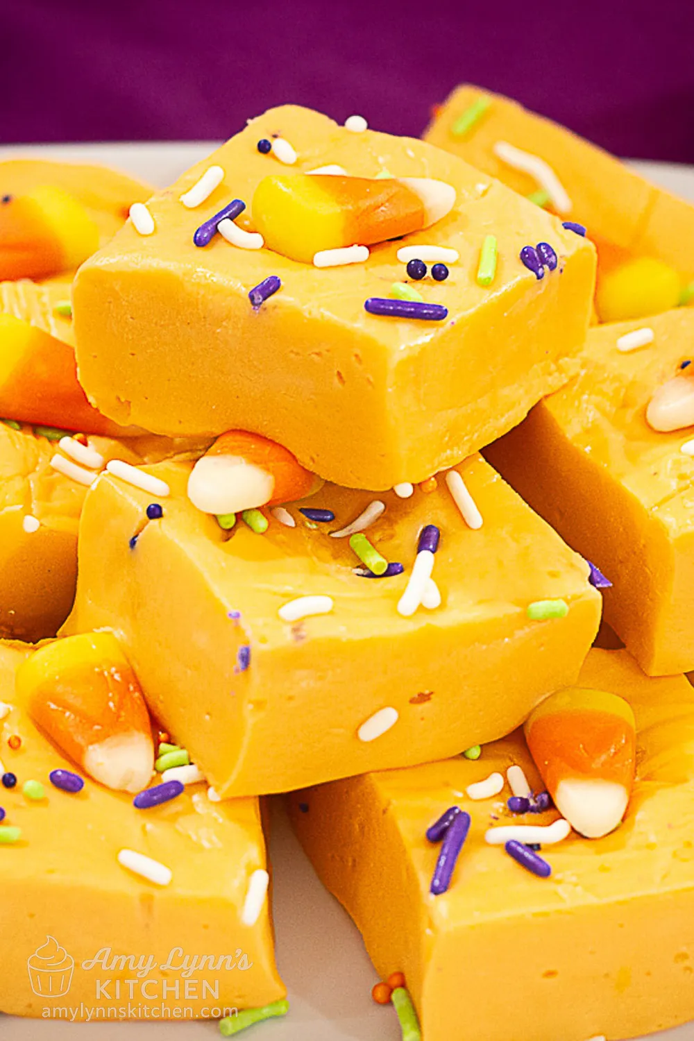 Easy Halloween Orange Fudge squares topped with candy corn and colorful sprinkles.