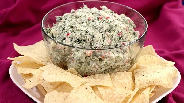Clear bowl filled with easy spinach dip with water chestnuts surrounded by fresh, crispy tortilla chips.