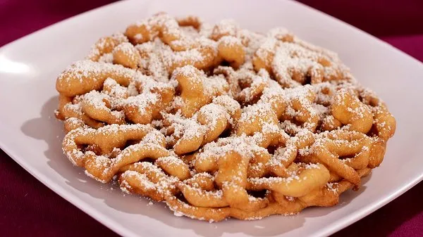 Funnel cake topped with powdered sugar on a white plate.