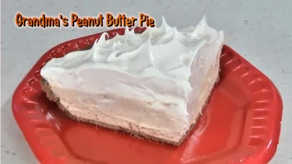 A slice of Grandma's peanut butter pie topped with whipped topping on a red plate.