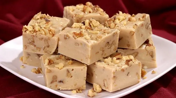 Maple walnut fudge stacked on a white plate.