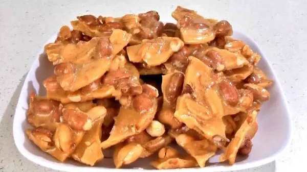 Amazing microwave peanut brittle stacked on a white plate.
