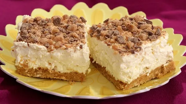 Two slices of no bake white chocolate cheesecake squares on a yellow plate.