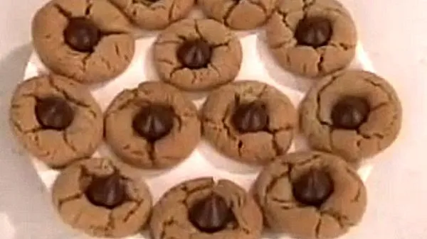 Peanut butter blossoms topped with a Hershey Kiss on a plate.
