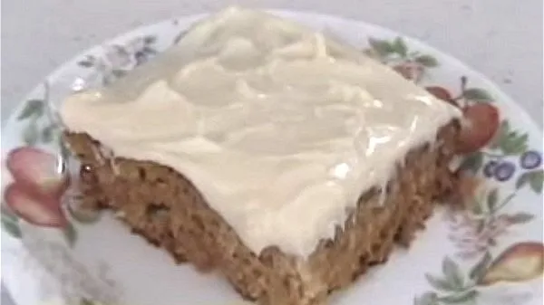 A piece of pineapple cream cake topped with a sweet cream cheese frosting on a plate.