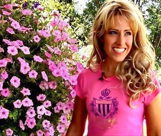 Amy smiling beside bright pink flowers