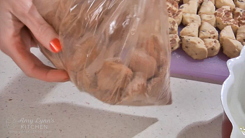 Place a handful of cut cinnamon roll pieces into the plastic bag, close and shake to evenly cover.