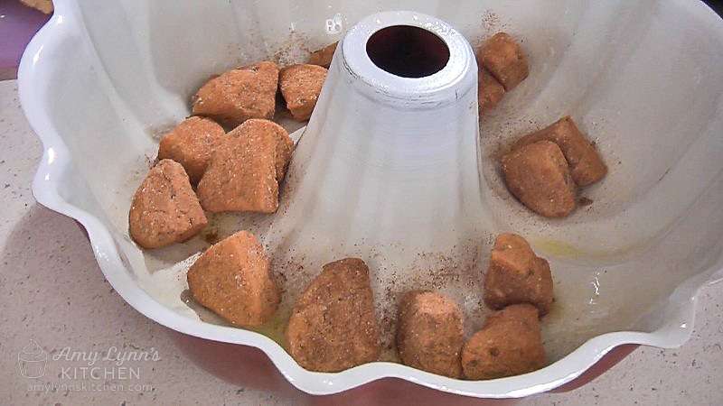Place coated cinnamon roll pieces into the bottom of your prepared bundt pan.