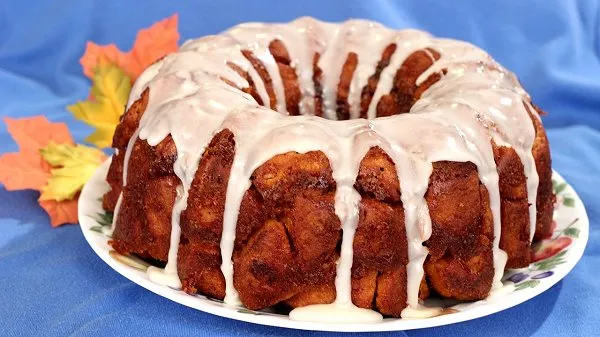 Pumpkin cinnamon roll monkey bread topped with icing on a plate.