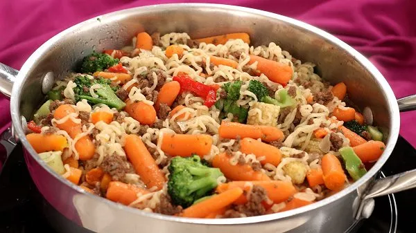Skillet full of ramen noodles and loaded with carrots and stir fry vegetables.