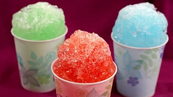 Three colorful snow cones in small cups.